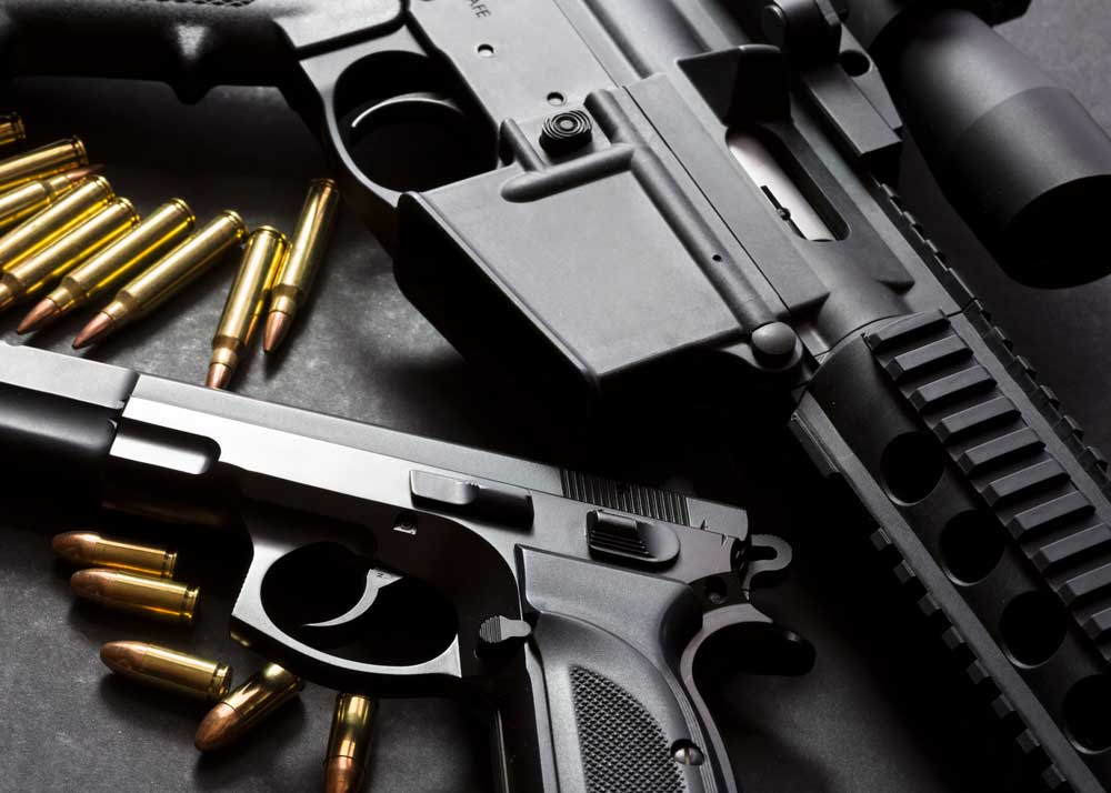 An image of a handgun and an automatic rifle with ammunition