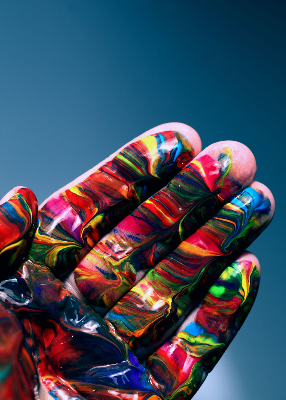 An image of the palm of a hand, painted all colors of the rainbow